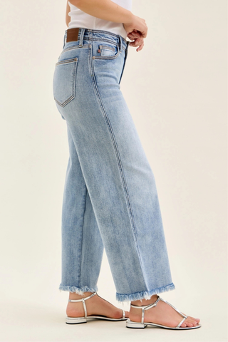 Judy Blue Mid Rise Ankle Hollywood Waistband Fray Hem Wide Leg Denim 82728REG Light blue jeans worn by a person on a beige background
