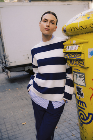 Person wearing a blue and white striped sweater standing next to a yellow mailbox with graffiti. b. young BYOtari Stripe Sweater