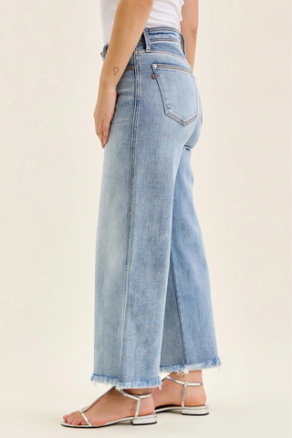 Judy Blue Mid Rise Ankle Hollywood Waistband Fray Hem Wide Leg Denim 82728REG Light blue jeans worn by a person on a beige background