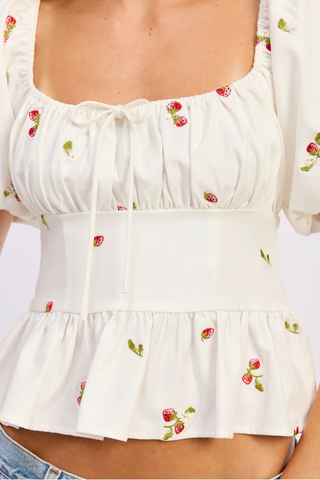 White blouse with strawberry pattern on a plain background En Saison Strawberry Kiss Embroidered Peplum Top
