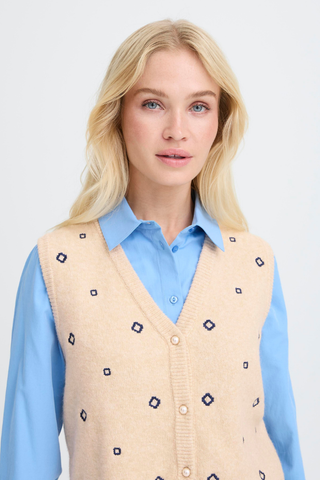BYNadika Embroidered Vest Woman wearing a beige patterned vest over a light blue shirt on a white background