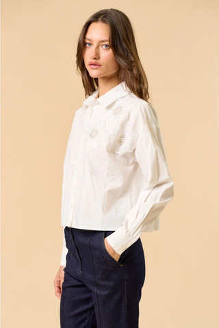 lalavon ILT6382 Off White Floral Appliqué Button Down Shirt  Woman wearing a white blouse and dark pants against a beige background
