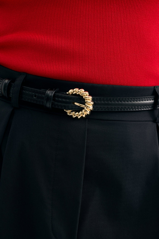 Leo & Ugo KEC073 Athena Leather Belt with Twisted Gold Buckle - Black Black pants with a gold belt buckle worn over a red top.