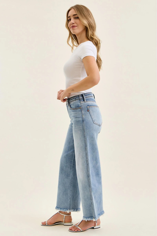 Judy Blue Mid Rise Ankle Hollywood Waistband Fray Hem Wide Leg Denim 82728REG Woman wearing light blue jeans and a white top on a plain background