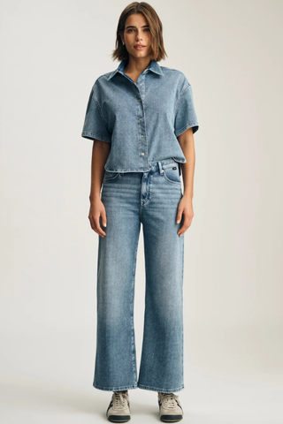 M1010914-A1427 Paloma Wide Leg Jeans Woman wearing a denim shirt and jeans on a plain background