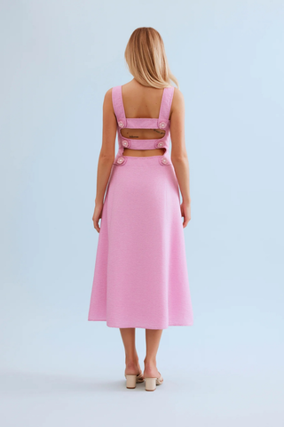 Leo & Ugo KER063 Nina Open Back Midi Dress Woman wearing a pink dress with cut-out back on a light blue background