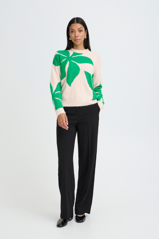 Woman wearing a green and white leaf-patterned sweater with black pants on a white background b. young BYOmea Flower Sweater
