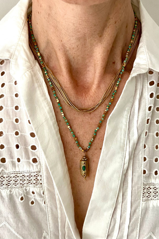 Ma Cocotte N37MAC Khiva Necklace Close-up of a person wearing a white shirt with a necklace featuring green beads and a pendant.