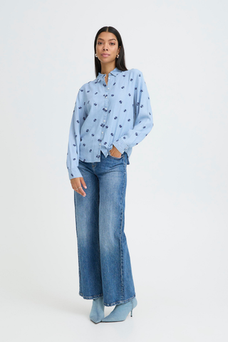 Woman wearing a light blue blouse with black patterns and wide-leg jeans on a white background b. young BYKosmo Boho Embroidered Shirt