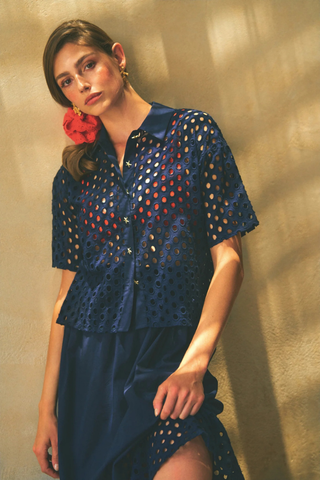 Leo & Ugo JE924 Laura Openwork Short Sleeve Blouse Woman wearing a blue perforated top against a beige wall