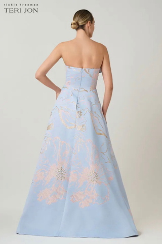Teri Jon 266025 Metallic Jacquard Strapless Side Bow A Line Skirt Gown Woman wearing a light blue strapless gown with floral embroidery on a plain background