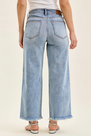 Judy Blue Mid Rise Ankle Hollywood Waistband Fray Hem Wide Leg Denim 82728REG Light blue jeans worn by a person on a beige background