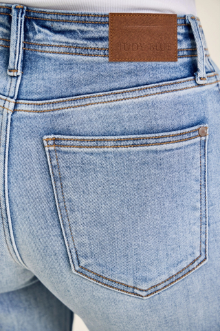Judy Blue Mid Rise Ankle Hollywood Waistband Fray Hem Wide Leg Denim 82728REG Close-up of blue jeans with a brown label on the back pocket.