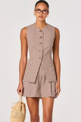 Woman wearing a checkered dress holding a woven bag on a plain background ASTR Karan Vest