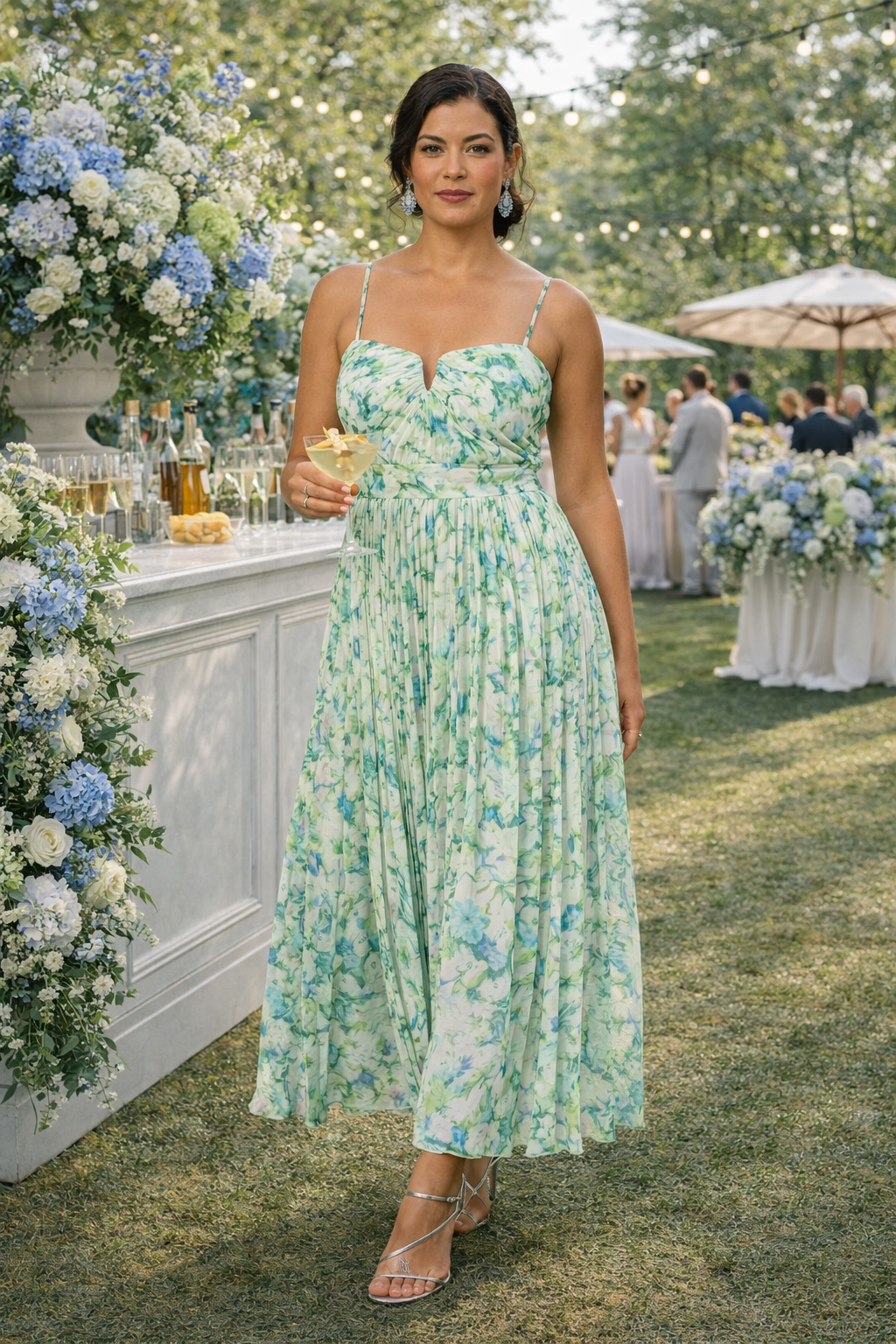 Woman in a floral dress standing outdoors at a social event with floral decorations and people in the background.