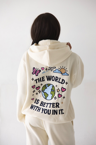 Happy Camp3r The World Is Better Zip Up Hoodie W303CRM-5 Person wearing a cream hoodie with a motivational message on the back against a white background