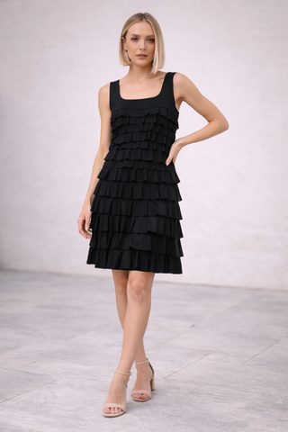 Isle Square Neck Cha Cha Dress Black Woman wearing a black tiered dress on a light gray background