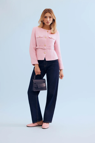 Leo & Ugo KE376 Salomé Elegant Belted Jacket - Pink Woman wearing a pink jacket and dark jeans holding a small handbag against a light blue background