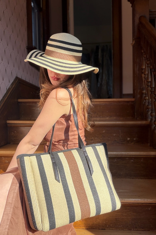 Leo & Ugo KEBH088 Neutral Striped Hat & Bag Combo Woman wearing a striped hat and holding a matching striped bag on wooden stairs.
