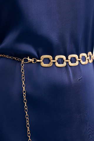 Leo & Ugo KEC072 Linda Gold Belt with Textured Links Gold chain belt on a blue fabric background