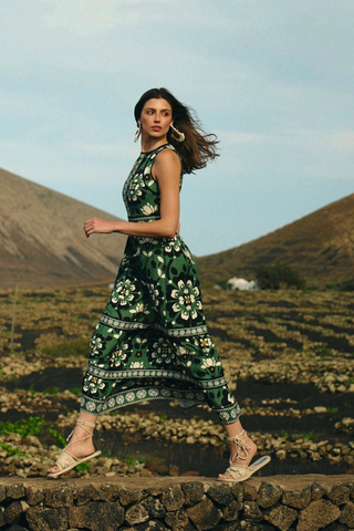 Leo & Ugo KER380 Floral Print Sleeveless Dress Woman in a green floral dress standing on a stone wall with a scenic background